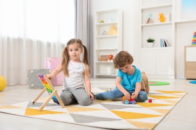 Photo of Cute little children playing with different toys on floor in kindergarten