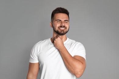 Man suffering from throat pain on light grey background