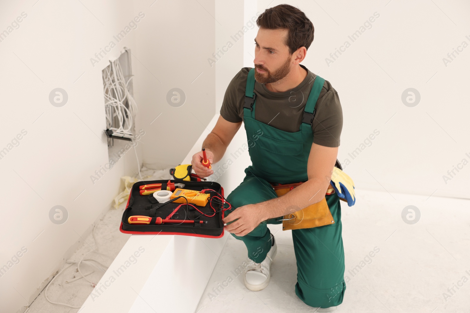 Photo of Electrician taking screwdriver from tool bag indoors