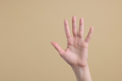Photo of Woman giving high five on light brown background, closeup. Space for text