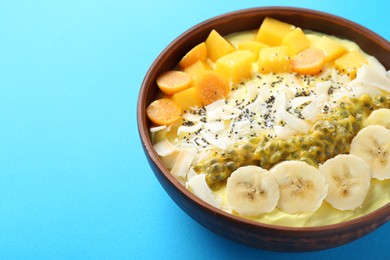 Photo of Tasty smoothie bowl with fresh fruits on light blue table, closeup. Space for text