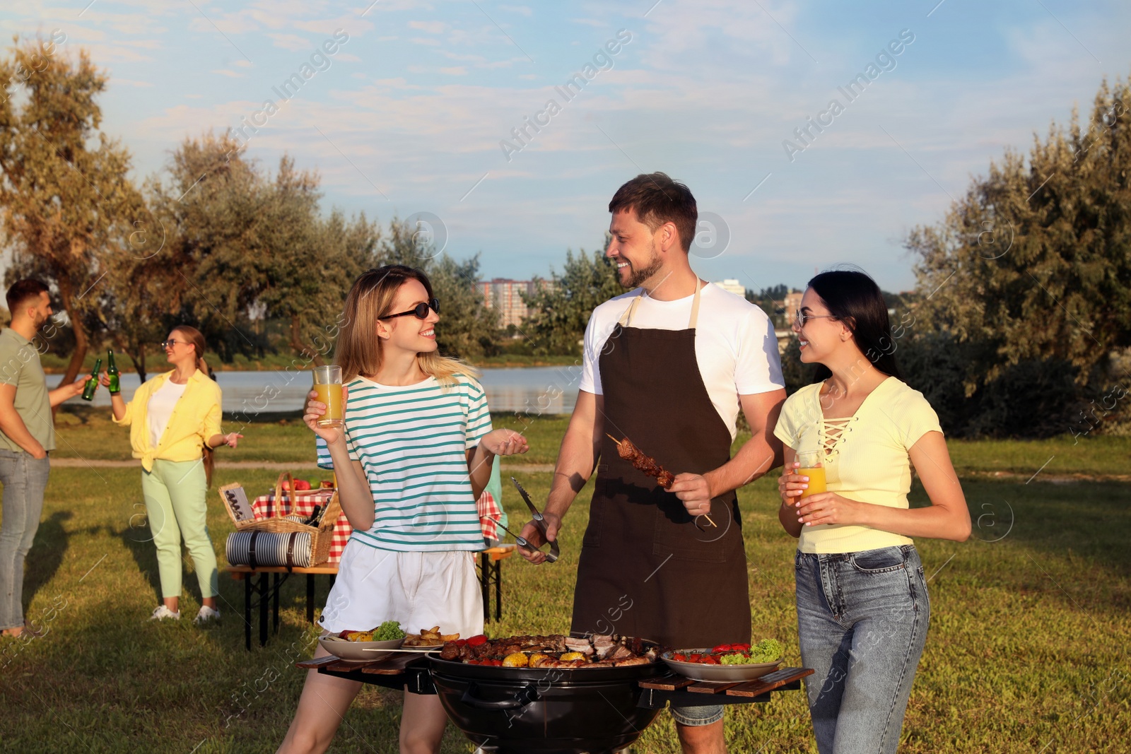 Photo of Group of friends cooking food on barbecue grill in park