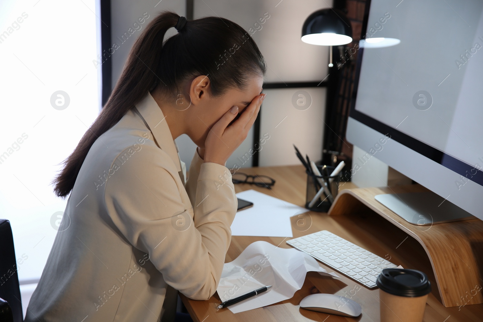 Photo of Stressed and tired young woman at workplace