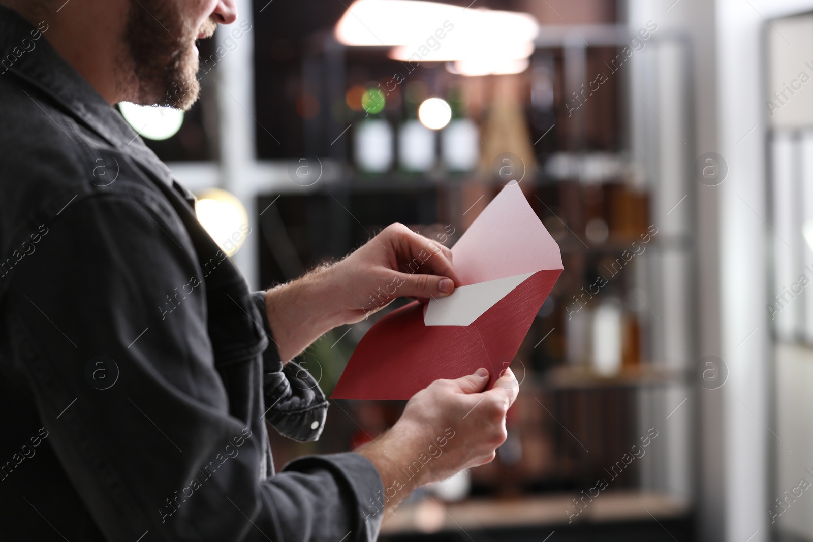 Photo of Man holding envelope with greeting card indoors, closeup