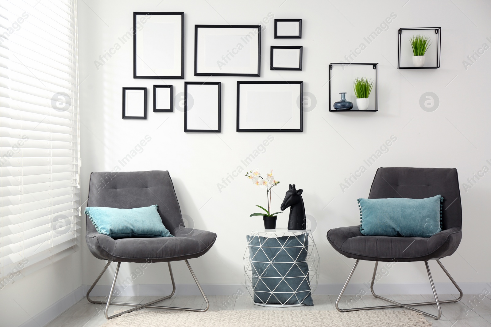 Photo of Stylish room interior with empty frames hanging on white wall and comfortable furniture