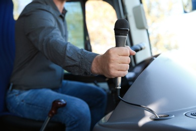 Professional driver holding microphone in bus. Passenger transportation