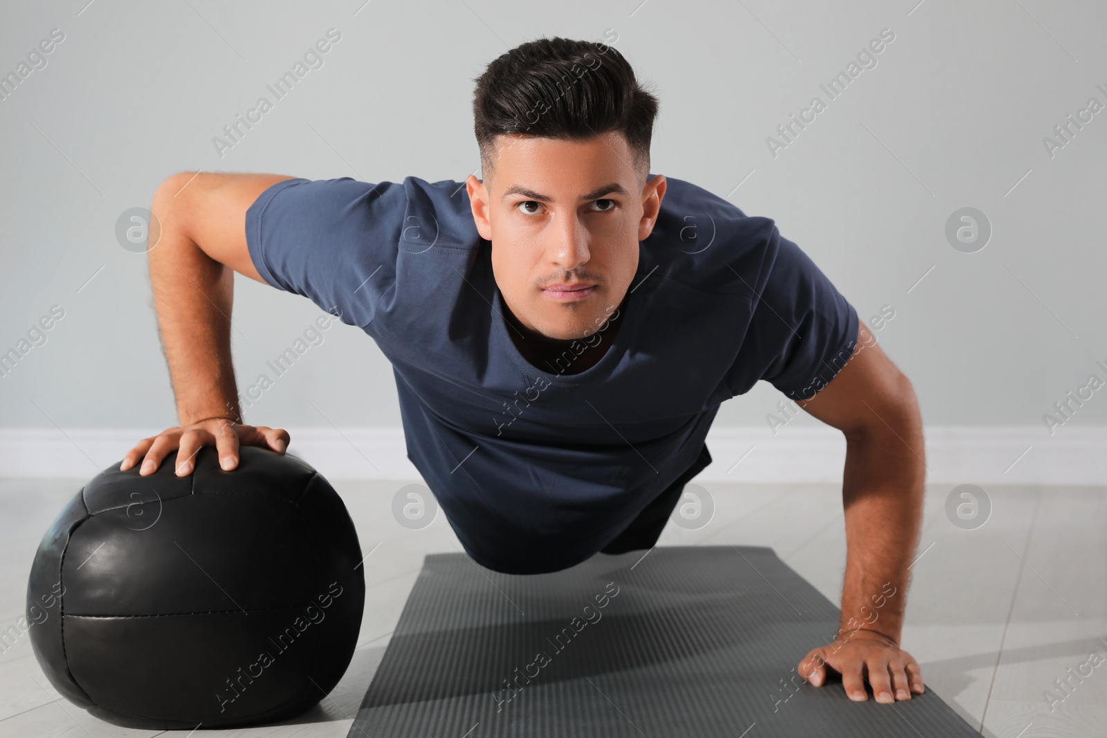 Photo of Athletic man doing push ups with medicine ball in modern gym