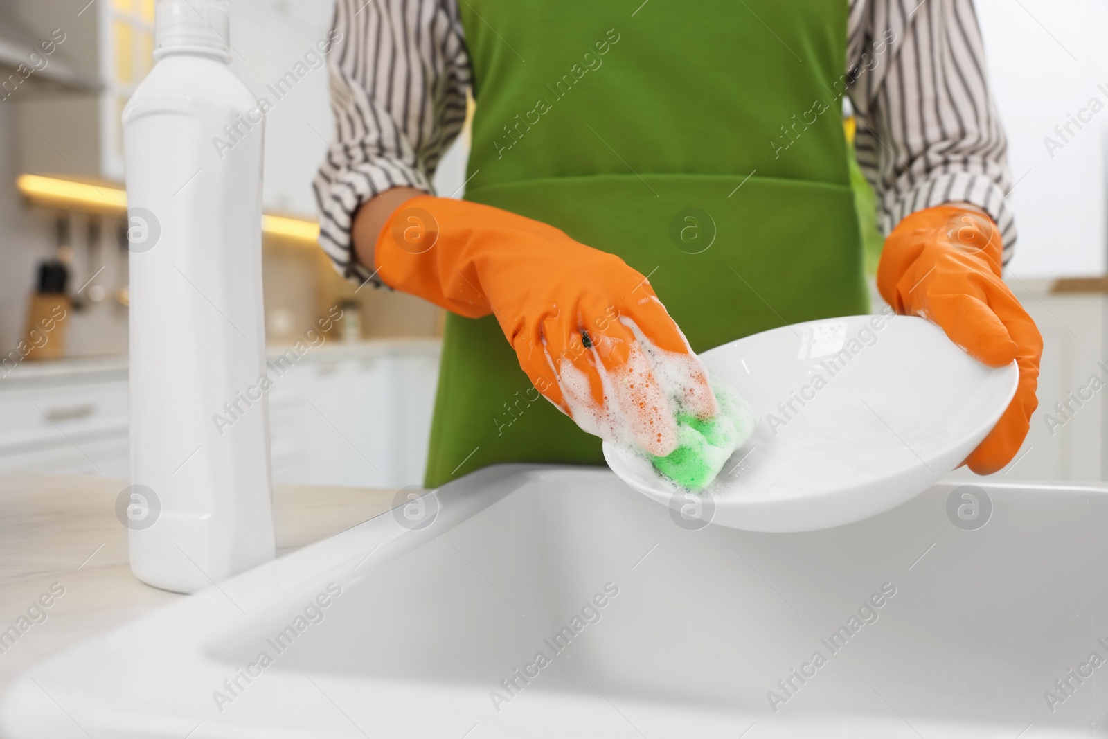 Photo of Woman washing plate above sink in modern kitchen, closeup