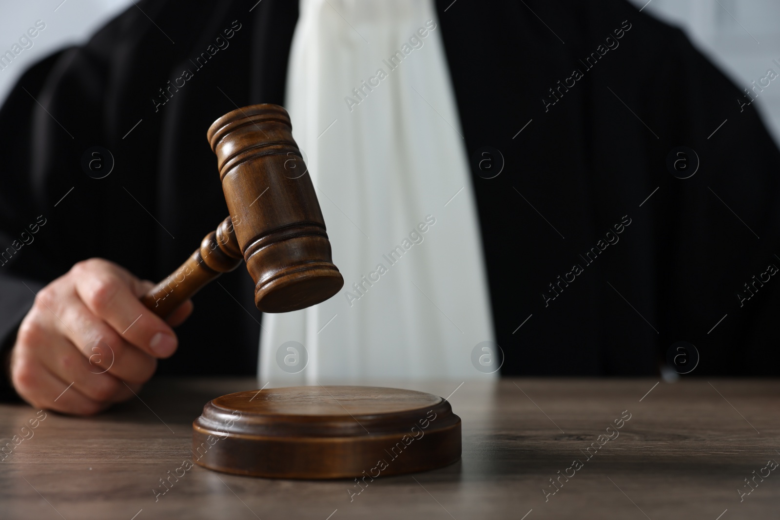 Photo of Judge with gavel sitting at wooden table, closeup