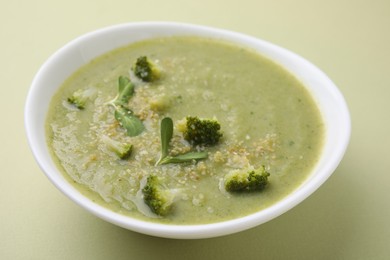 Delicious broccoli cream soup on olive background, closeup