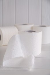 Photo of Soft toilet paper rolls on white wooden table