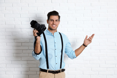Photo of Professional photographer working near white brick wall in studio