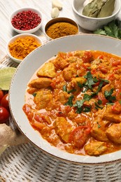 Delicious chicken curry and ingredients on wooden table