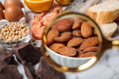 Different products with magnifier focused on almonds, closeup. Food allergy concept