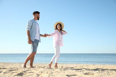 Happy young couple walking on beach near sea. Honeymoon trip