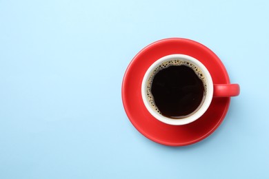 Photo of Aromatic coffee in cup on light blue background, top view. Space for text