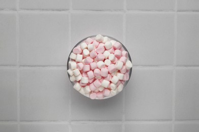 Photo of Bowl with delicious marshmallows on white tiled table, top view