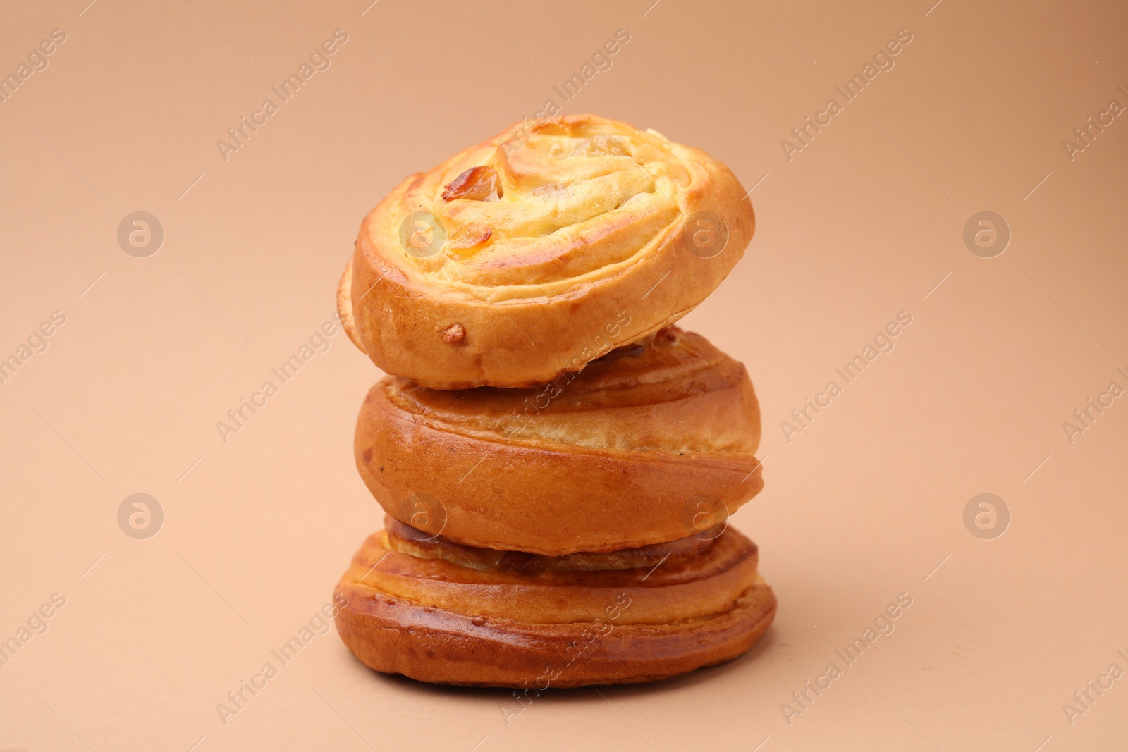 Photo of Stack of delicious rolls with raisins on beige background. Sweet buns