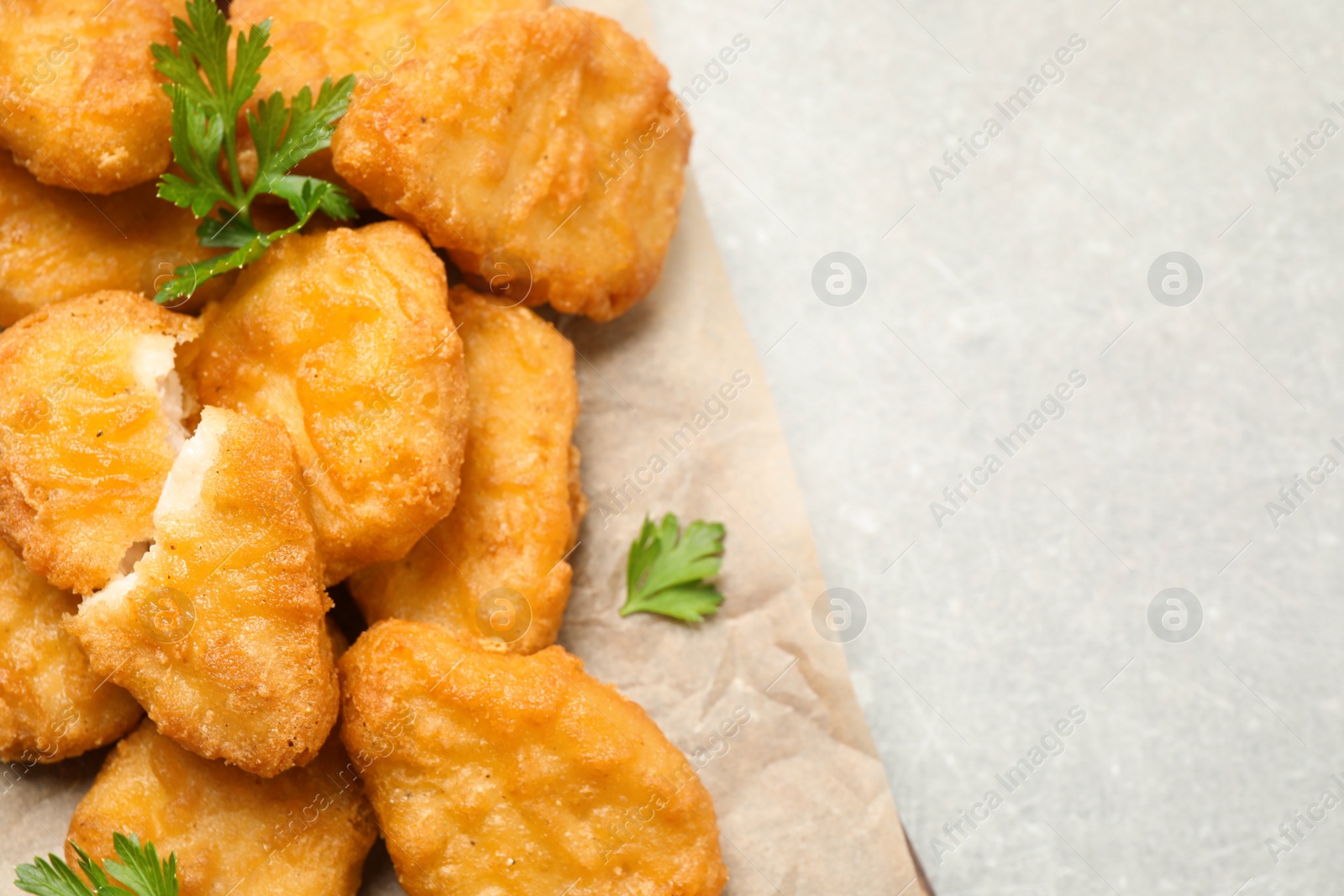 Photo of Tasty fried chicken nuggets on light grey table, top view. Space for text