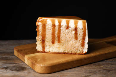 Slice of delicious cake with caramel sauce on wooden table