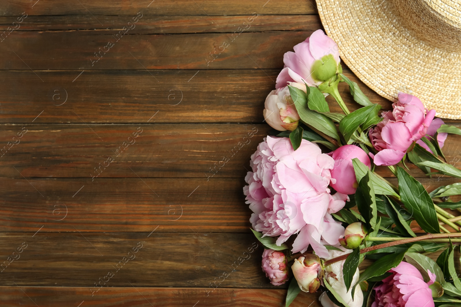 Photo of Beautiful peonies and straw hat on wooden table, flat lay. Space for text