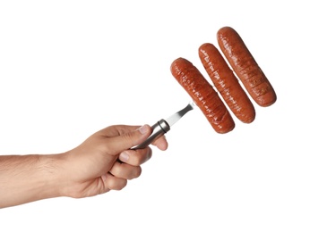 Man holding fork with grilled sausages on white background, closeup. Barbecue food