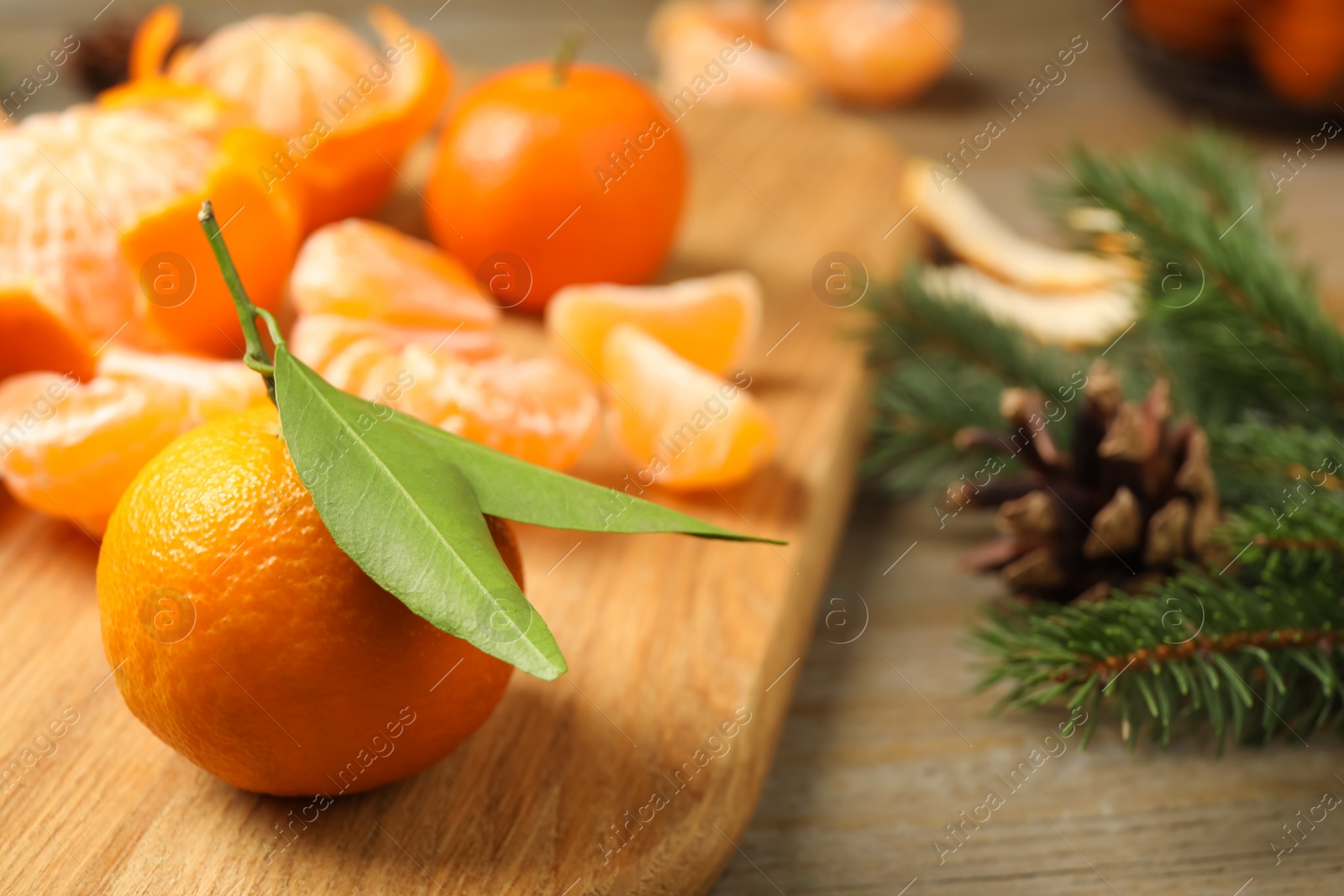 Photo of Fresh tangerines and fir tree branches on wooden table, closeup. Christmas atmosphere