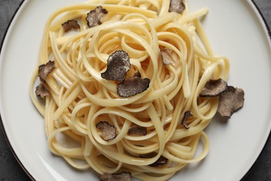 Photo of Tasty fettuccine with truffle on plate, closeup. Top view
