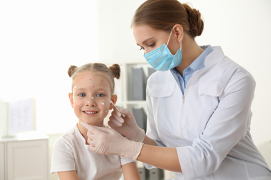 Photo of Doctor applying cream onto skin of little girl with chickenpox in clinic. Varicella zoster virus