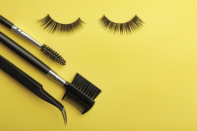 Flat lay composition of professional makeup tools and false eyelashes on color background, space for text