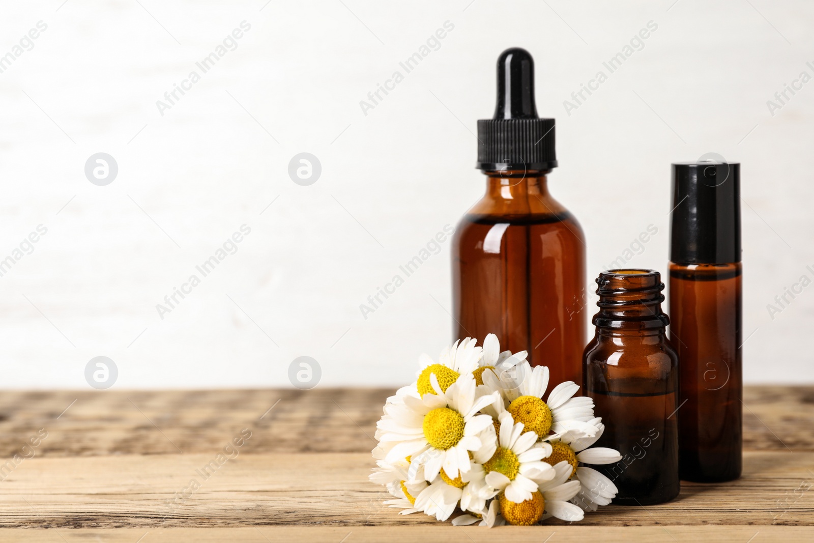 Photo of Composition with bottles of chamomile essential oil on table. Space for text