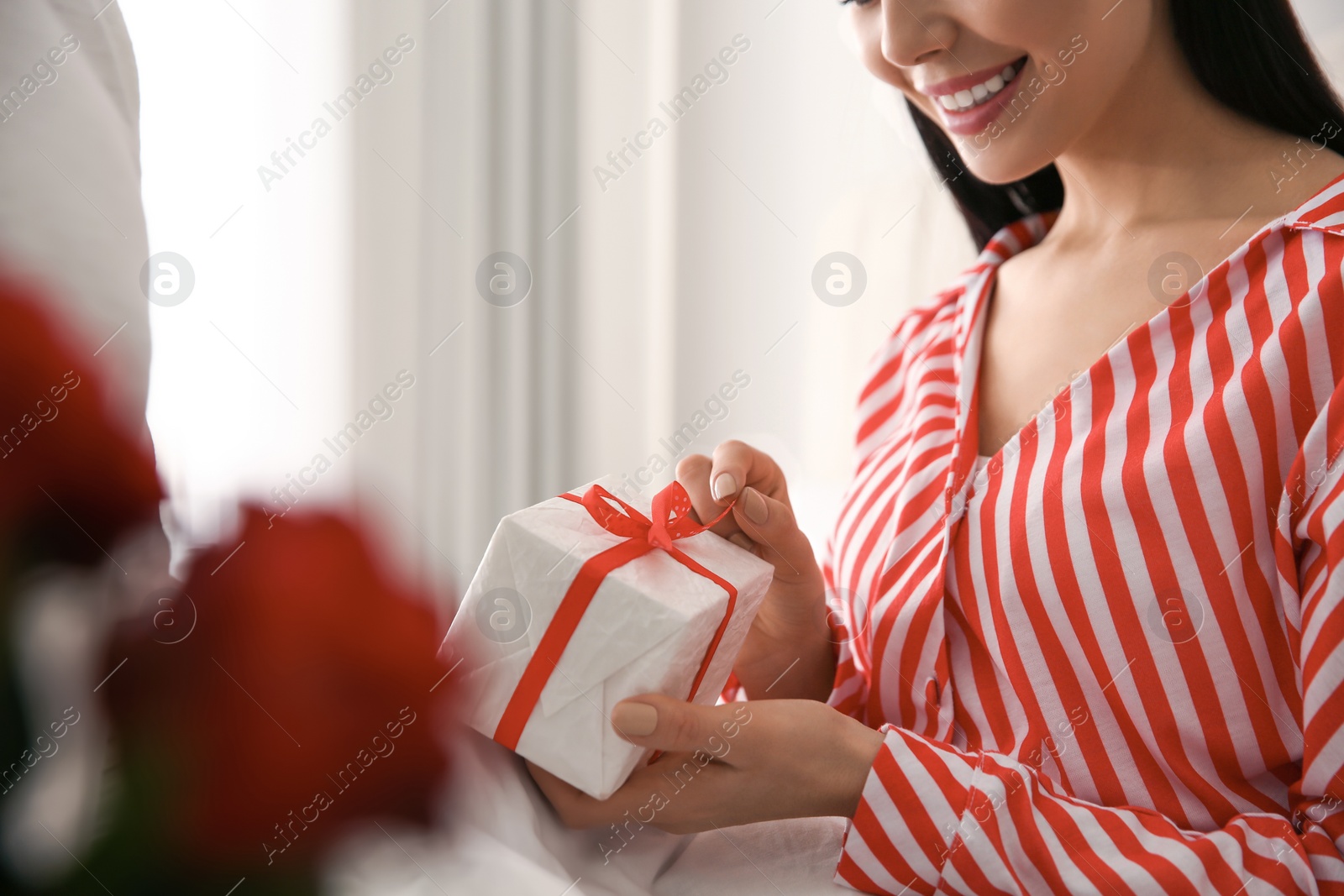 Photo of Lovely couple with gift box at home, closeup. Valentine's day celebration