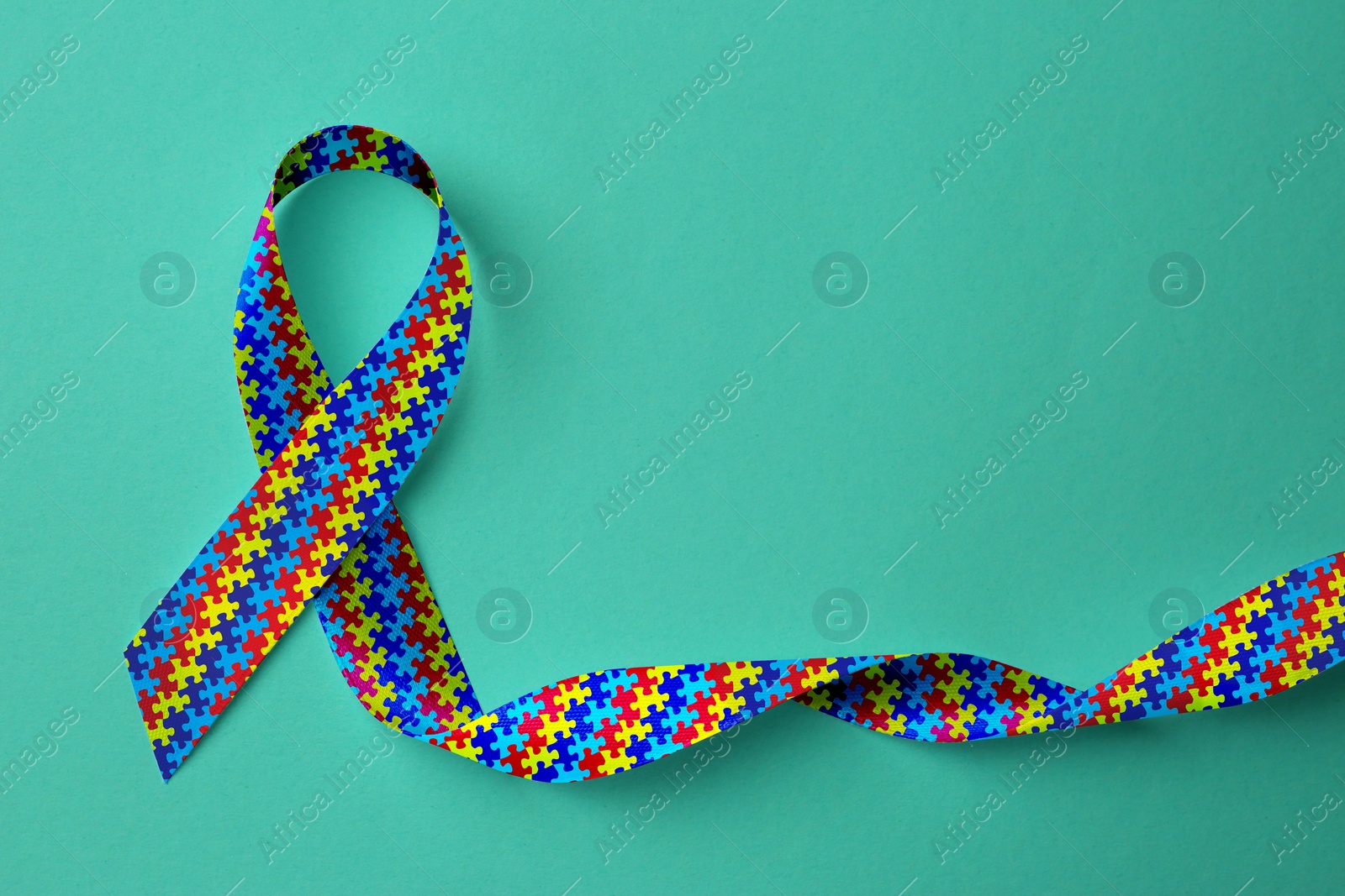 Image of World Autism Awareness Day. Colorful puzzle ribbon on cyan background, top view