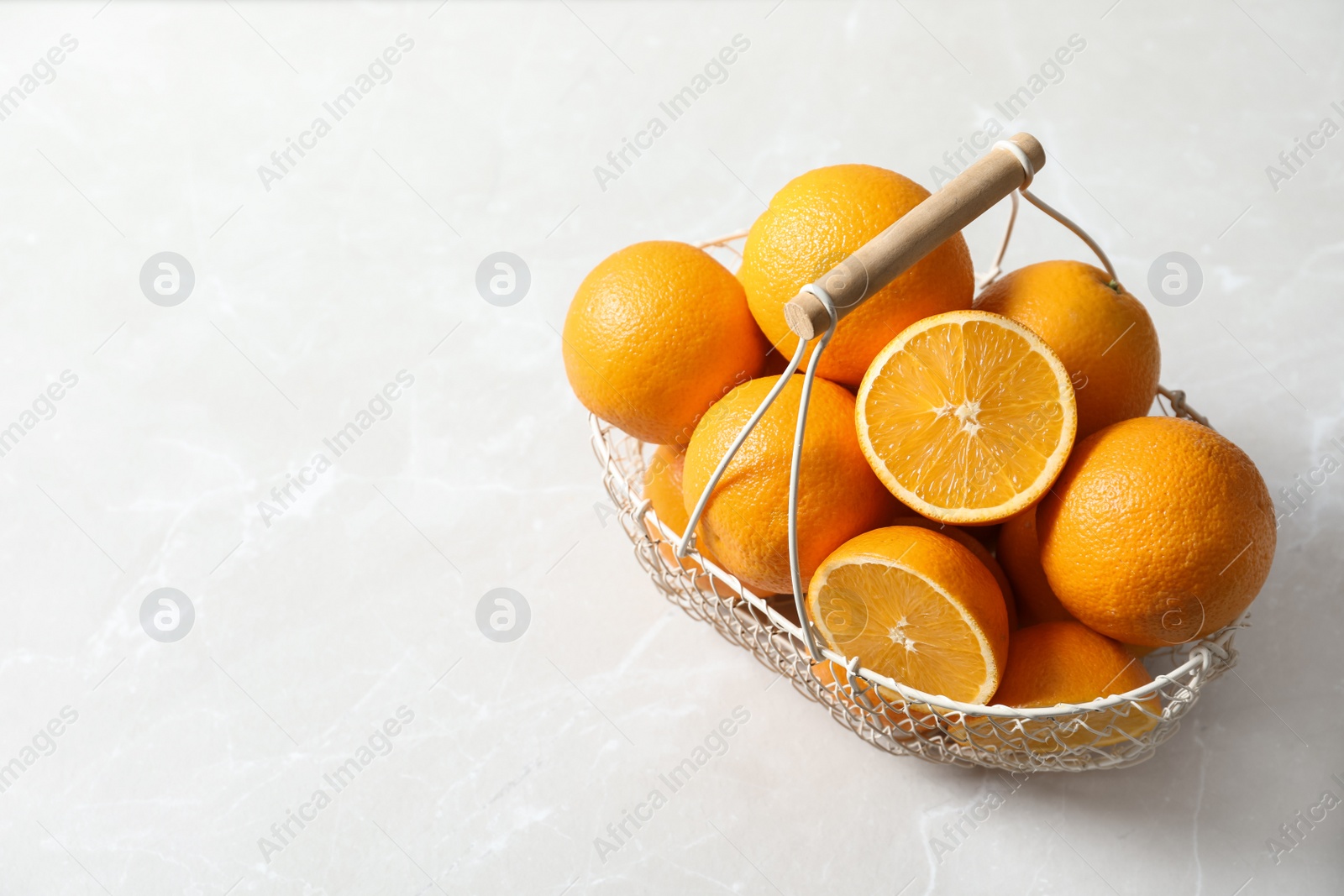 Photo of Basket with ripe oranges on light background. Space for text