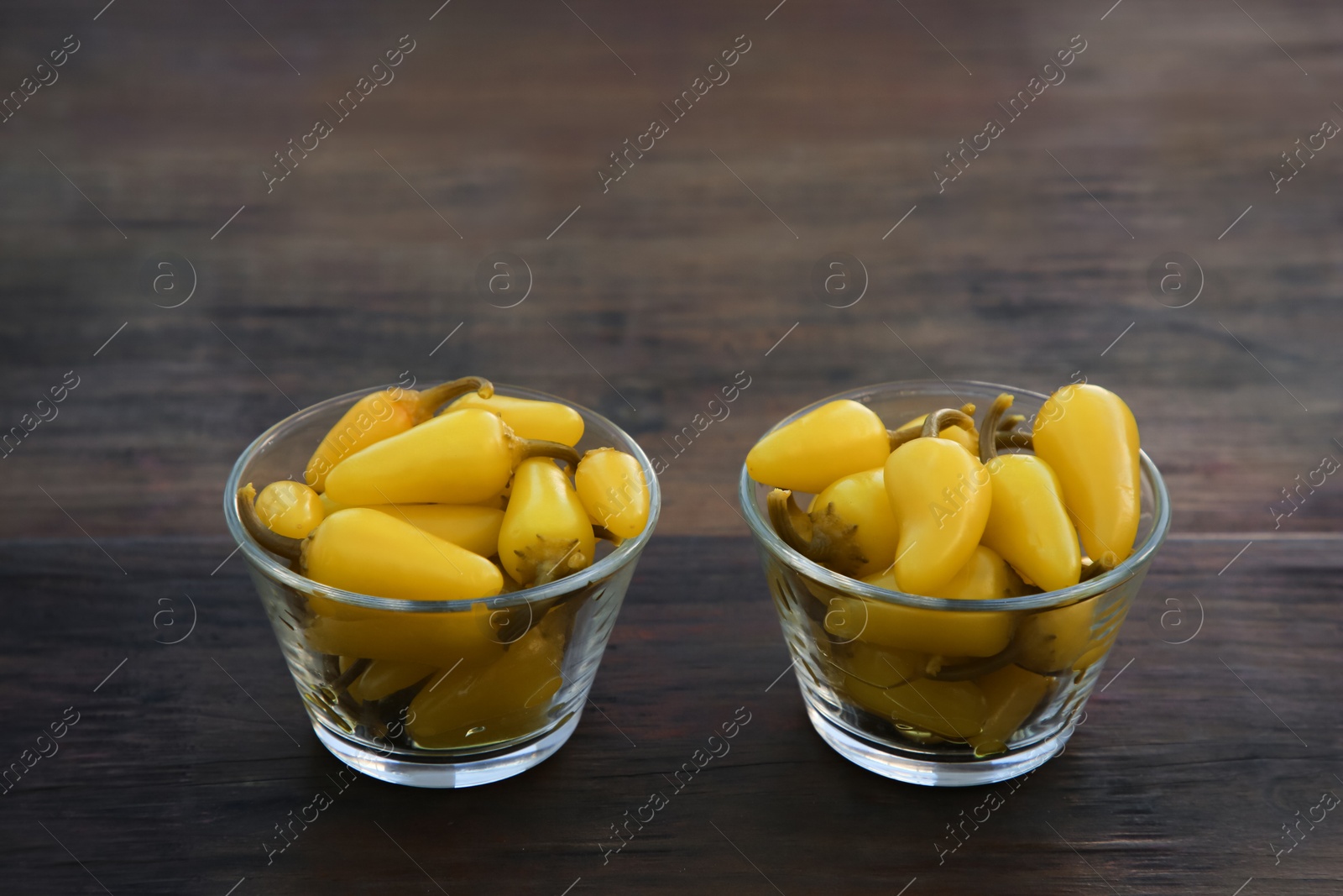 Photo of Pickled yellow jalapeno peppers on wooden table