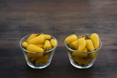 Photo of Pickled yellow jalapeno peppers on wooden table