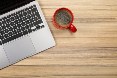 Modern laptop and cup of coffee on wooden table, flat lay. Space for text