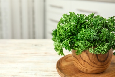 Photo of Bowl with fresh green parsley on white wooden table indoors. Space for text