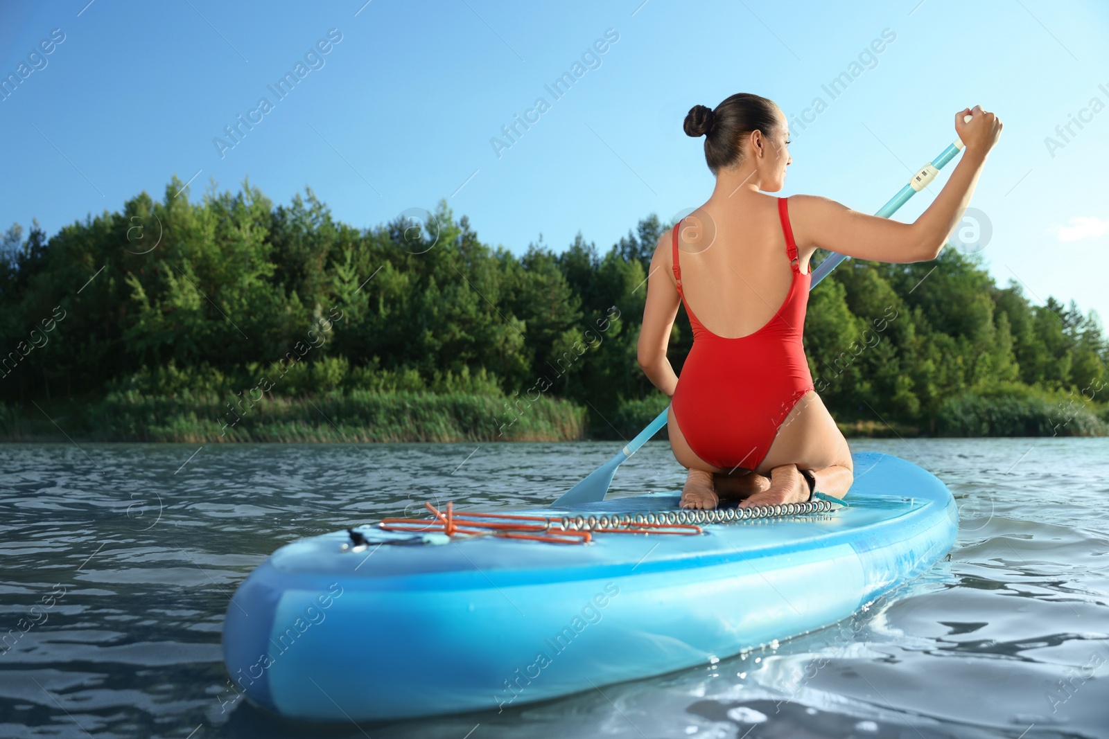 Photo of Woman paddle boarding on SUP board in river, back view