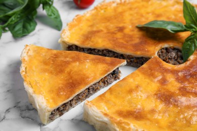 Delicious pie with minced meat and basil on white marble table, closeup