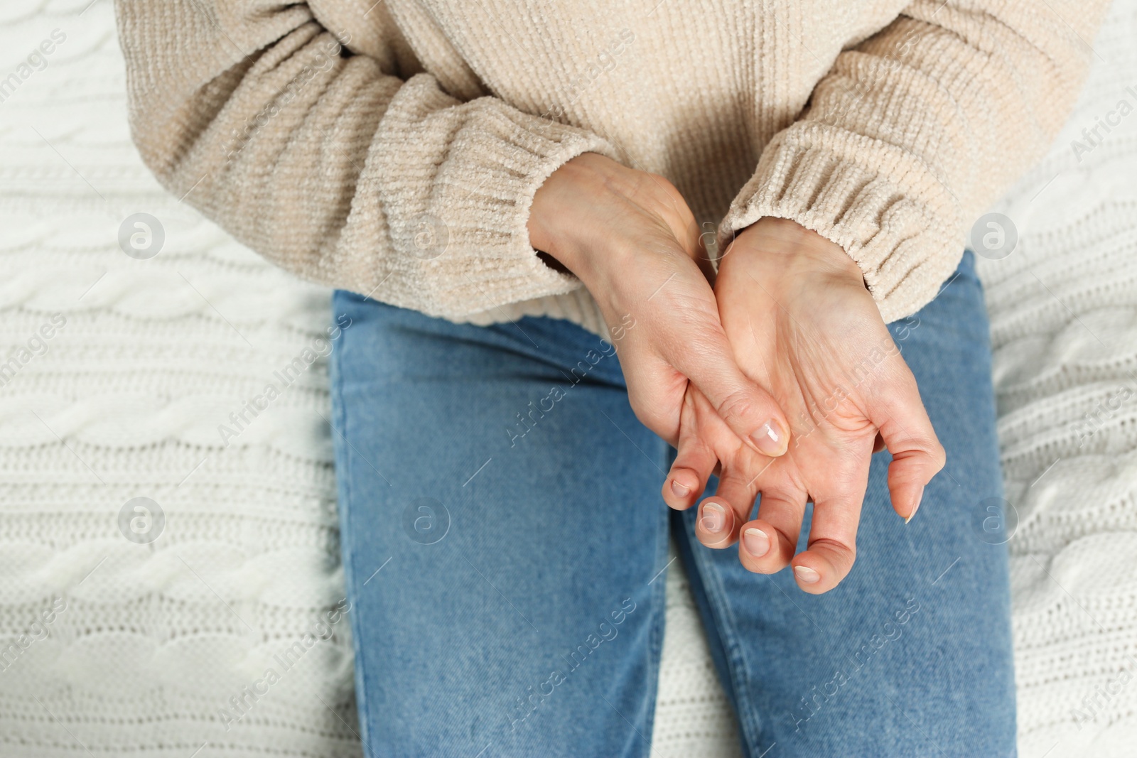 Photo of Woman suffering from trigger finger on bed, closeup