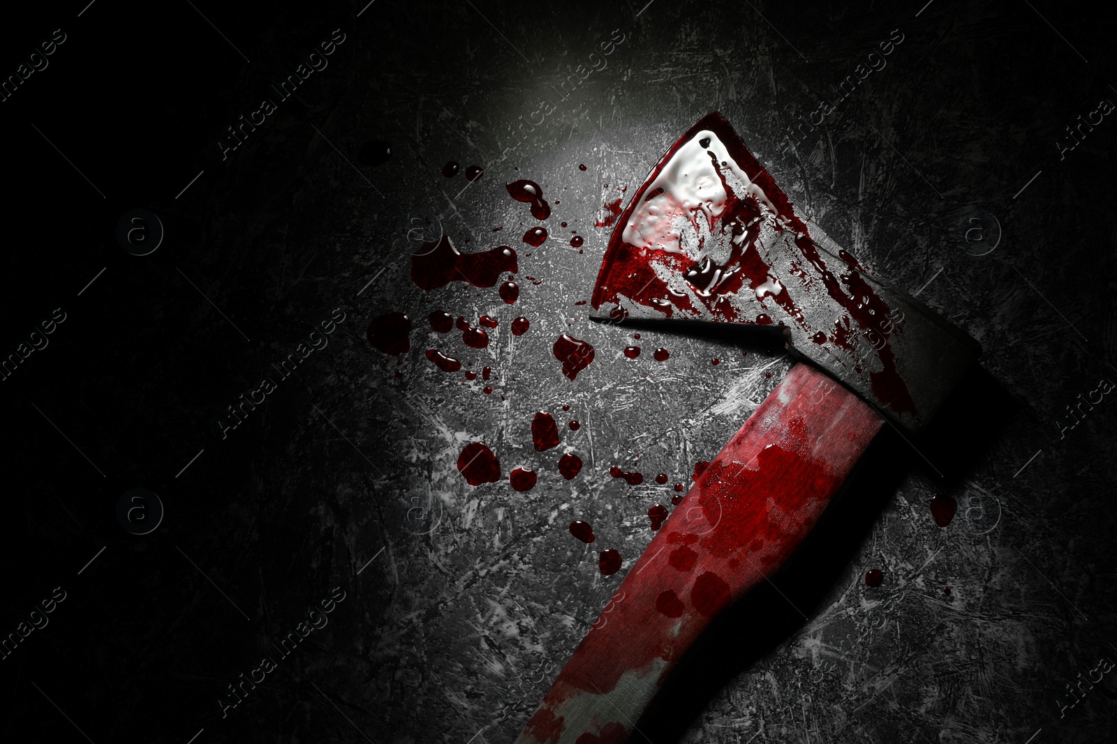 Photo of Axe with blood on dark gray textured surface in darkness, top view. Space for text
