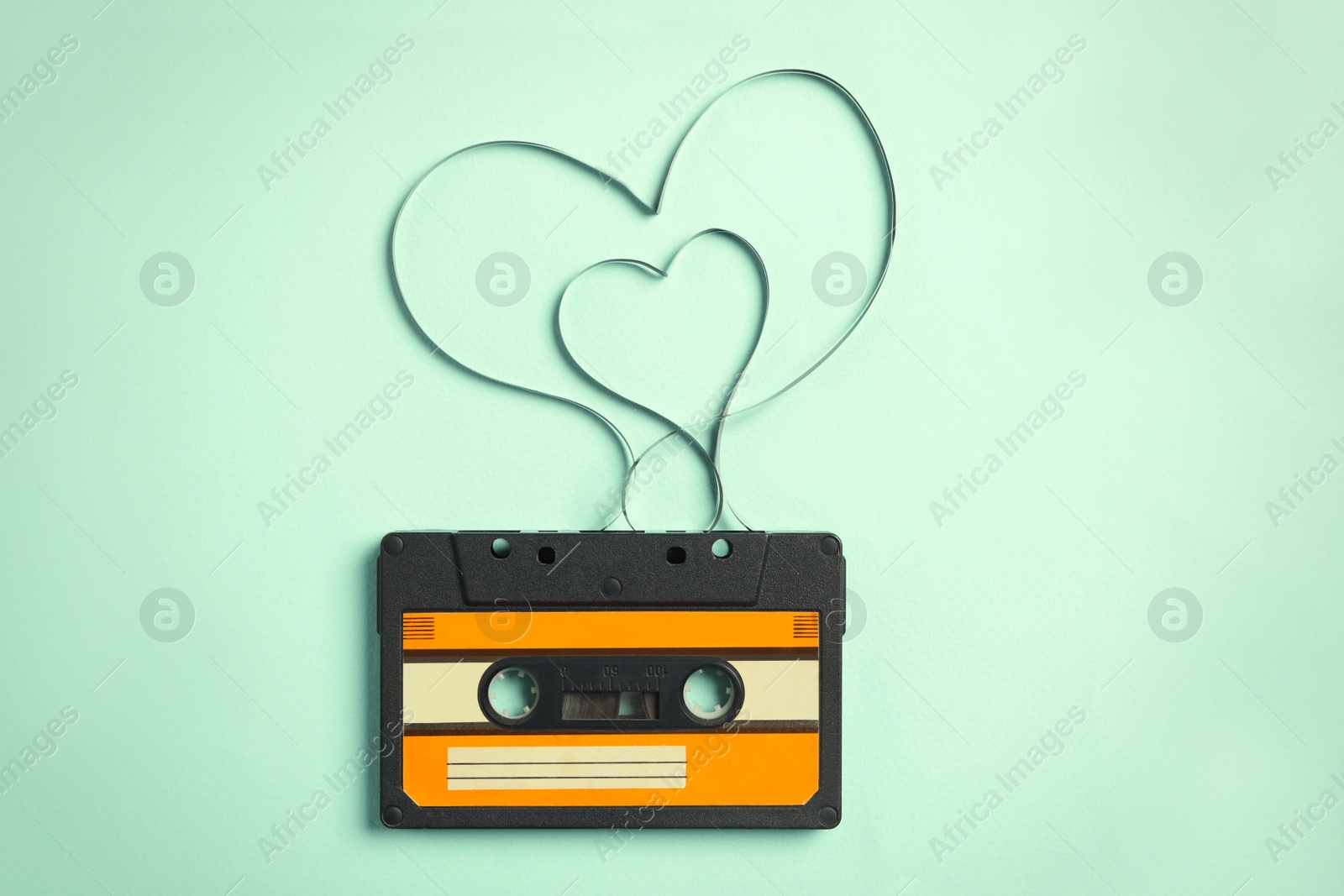 Photo of Music cassette and hearts made with tape on turquoise background, top view. Listening love song