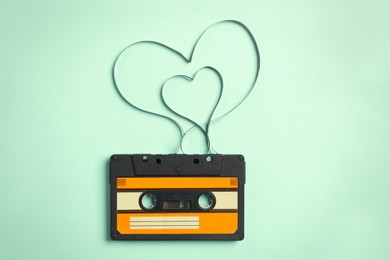 Photo of Music cassette and hearts made with tape on turquoise background, top view. Listening love song