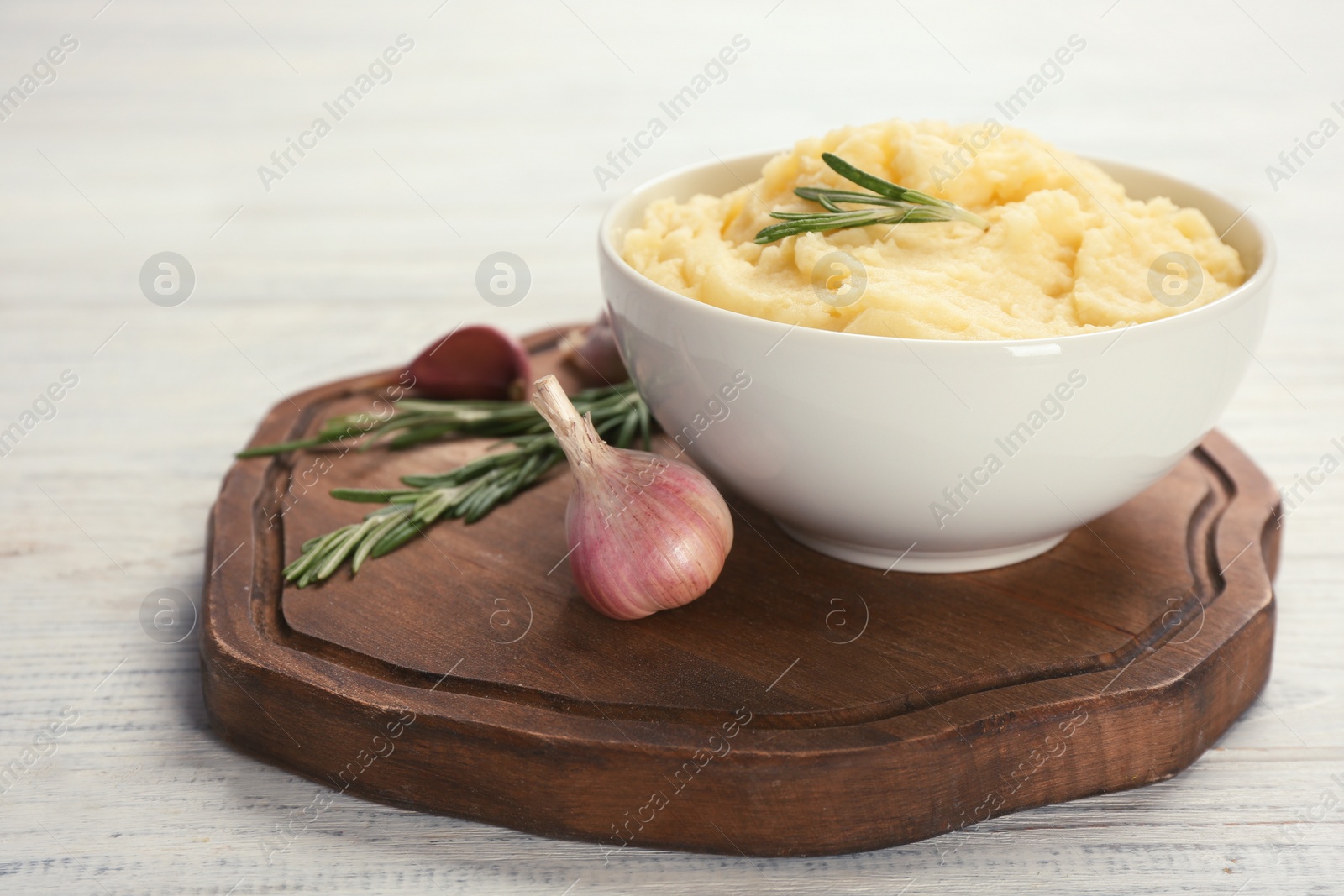 Photo of Bowl with mashed potatoes on wooden board