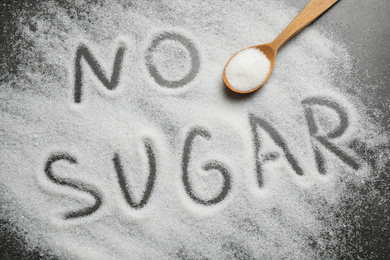 Flat lay composition with phrase NO SUGAR and spoon on grey table