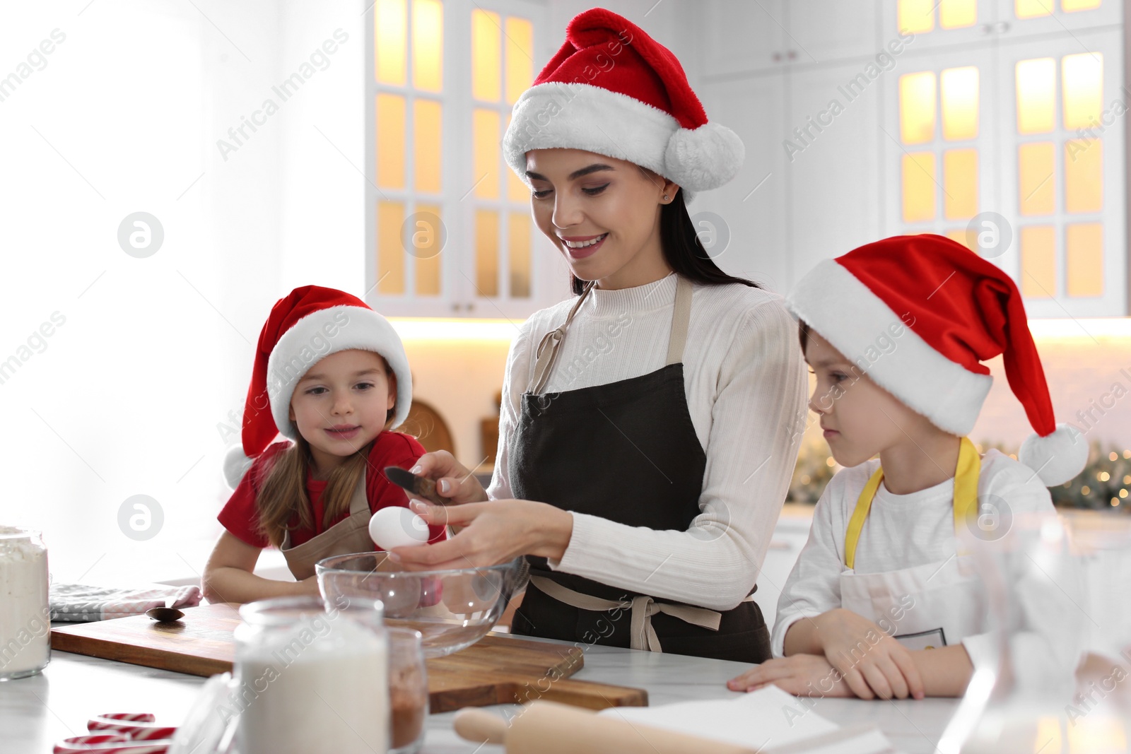 Photo of Mother with her cute little children making Christmas cookies in kitchen