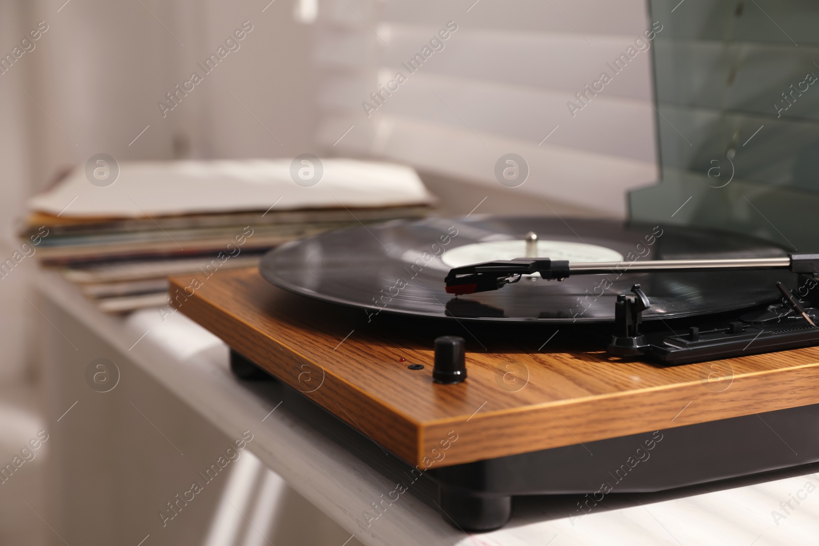 Photo of Stylish turntable with vinyl disc on windowsill in room, closeup