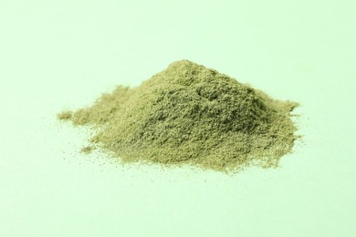 Photo of Pile of wheat grass powder on green table, closeup
