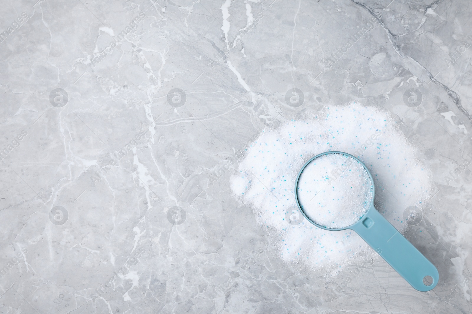 Photo of Scoop with laundry powder on marble background, top view. Space for text